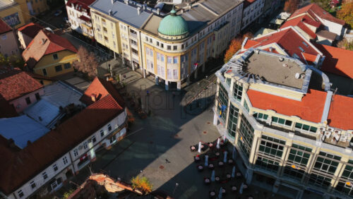 Video – Aerial drone view of Trg Slobode, Tuzla’s largest city square, featuring its central fountain, open plaza, surrounding cafes, and historic facades. Bosnia and Herzegovina - Starpik Stock