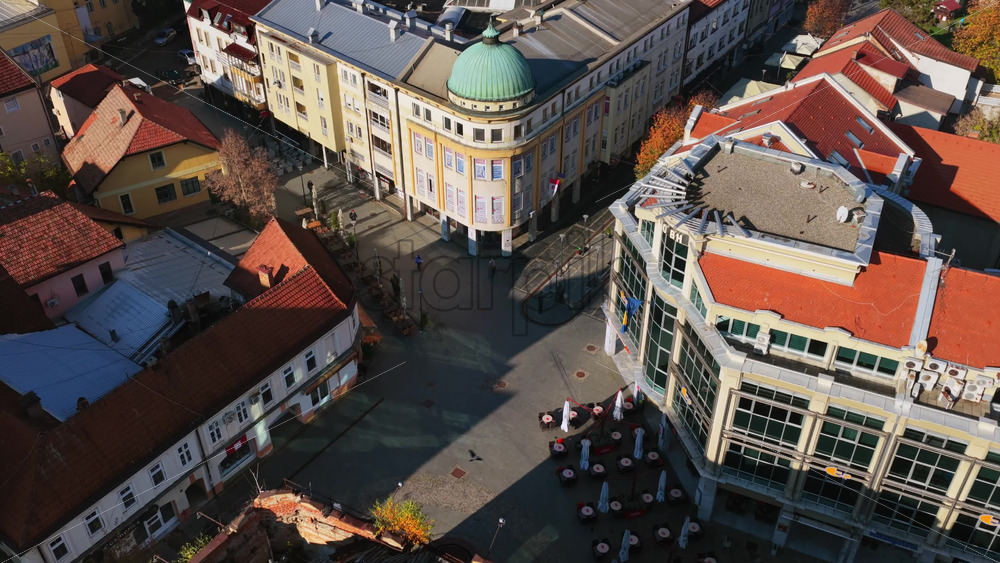 Video – Aerial drone view of Trg Slobode, Tuzla’s largest city square, featuring its central fountain, open plaza, surrounding cafes, and historic facades. Bosnia and Herzegovina - Starpik Stock