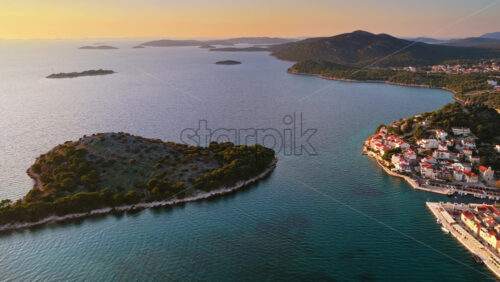 Video – Aerial drone view of Tribunj, with marinas full of boats and warm sunlight reflecting across the sea. Croatia - Starpik Stock