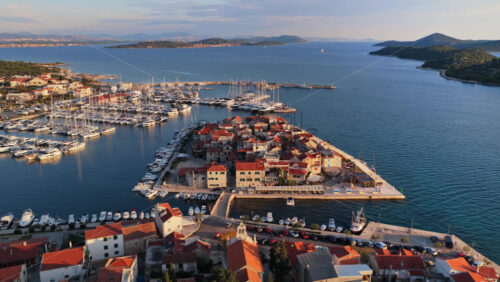 Video – Aerial drone view of Tribunj, with marinas full of boats and warm sunlight reflecting across the sea. Croatia - Starpik Stock