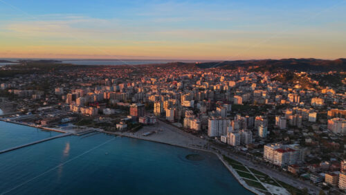 Video – Aerial drone view of Vlora, Albania, showcasing the city’s dense coastal skyline, mountain backdrop, and turquoise seafront - Starpik Stock