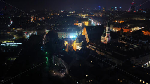 Video – Aerial drone view of Warsaw’s Old Town toward the Srodmiescie district, with bright city lights and residential buildings visible below - Starpik Stock