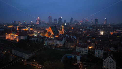 Video – Aerial drone view of Warsaw’s Old Town with illuminated historic buildings and the modern financial district skyline glowing in the distance - Starpik Stock