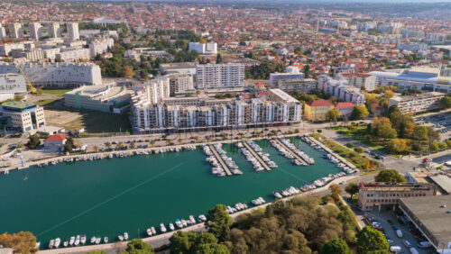 Video – Aerial drone view of Zadar’s marina filled with yachts and small boats, surrounded by modern residential and commercial buildings - Starpik Stock