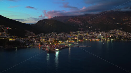 Video – Aerial drone view of a Budva illuminated by scattered building and street lights at night. Montenegro - Starpik Stock