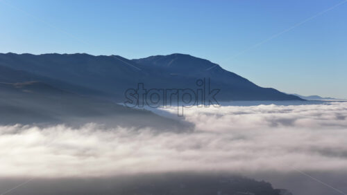 Video – Aerial drone view of a Galichica mountain ridge rising above a sea of clouds, with soft layers of fog covering the valley below - Starpik Stock