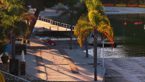 Video – Aerial drone view of a beachfront area in Ksamil, with palm trees, colorful pedal boats, and calm water reflecting the warm morning light - Starpik Stock