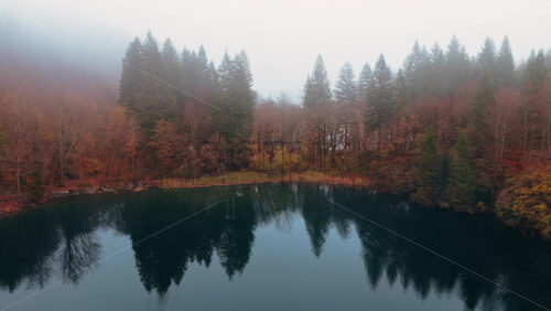 Video – Aerial drone view of a calm lake surrounded by dense autumn forest under a layer of morning fog in Plitvice Lakes National Park, Croatia - Starpik Stock
