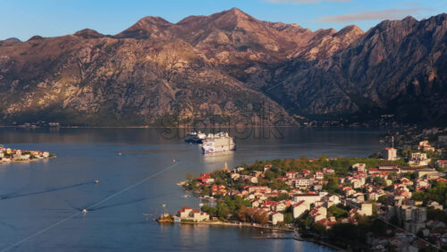 Video – Aerial drone view of a cruise ship anchored in the Bay of Kotor with mountains glowing in soft light - Starpik Stock