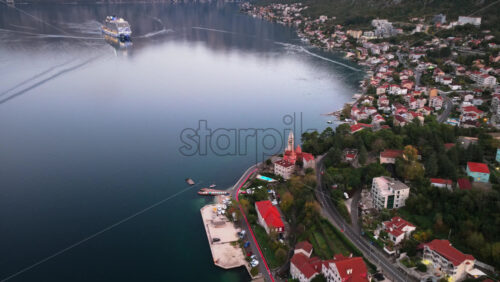 Video – Aerial drone view of a cruise ship navigating the Bay of Kotor, with surrounding coastal villages and mountains reflecting in calm water - Starpik Stock