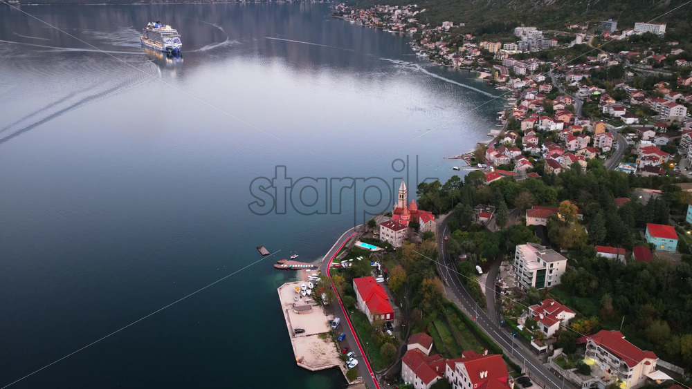 Video – Aerial drone view of a cruise ship navigating the Bay of Kotor, with surrounding coastal villages and mountains reflecting in calm water - Starpik Stock