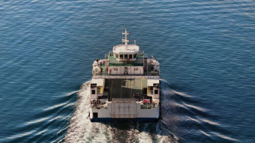 Video – Aerial drone view of a ferry traveling across smooth blue water, producing rippling white waves behind it - Starpik Stock