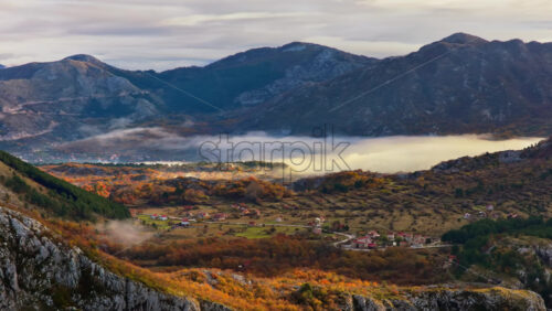 Video – Aerial drone view of a high valley with low flying fog drifting between mountain ridges - Starpik Stock