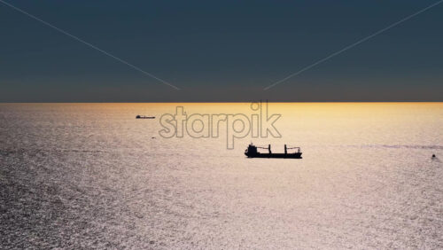Video – Aerial drone view of a large cargo ships silhouetted against the shimmering, golden water of the Adriatic Sea - Starpik Stock