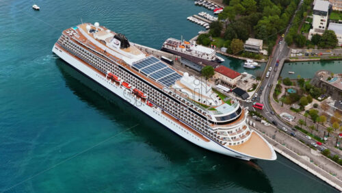 Video – Aerial drone view of a large cruise ship docked at the Kotor port, with buses, marina, and waterfront infrastructure visible - Starpik Stock