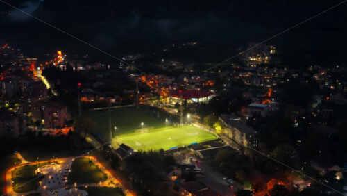 Video – Aerial drone view of a lit football field and surrounding city streets at night in the Bay of Kotor - Starpik Stock