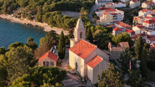 Video – Aerial drone view of a small stone church with a bell tower at golden hour sunset in Tribunj, Croatia - Starpik Stock