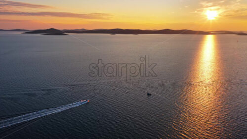 Video – Aerial drone view of a small white speedboat cuts across deep blue water, leaving a bright trail behind it. Adriatic sea, Croatia - Starpik Stock