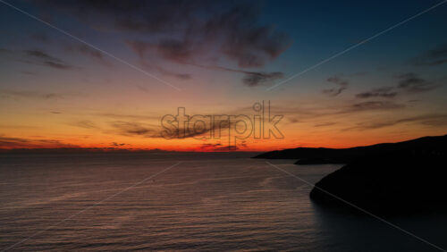 Video – Aerial drone view of a vivid sunset over calm open sea, with warm orange and red tones glowing across the horizon. Montenegro - Starpik Stock