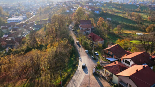 Video – Aerial drone view of a winding road through a hilly residential zone, with scattered homes, autumn foliage, and expansive countryside views in Bosnia and Herzegovina - Starpik Stock