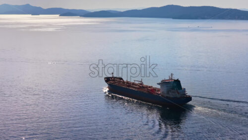 Video – Aerial drone view of an oil tanker traveling across open Adriatic waters with distant mountain ridges and coastal towns visible on the horizon - Starpik Stock