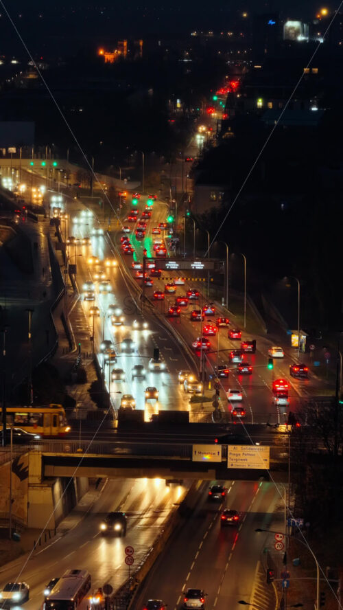 Video – Aerial drone view of busy Warsaw traffic with cars and trams moving along illuminated city roads . Vertical - Starpik Stock