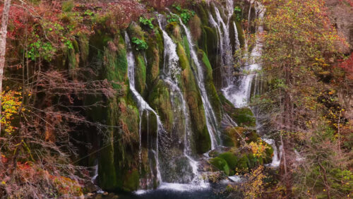 Video – Aerial drone view of cascading waterfalls flowing over moss covered cliffs and lush vegetation in Plitvice Lakes National Park, Croatia - Starpik Stock