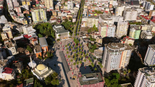 Video – Aerial drone view of central Durres showing the yellow domed Islam Iliaz Mosque, Liria Square with palm trees arranged in rows, surrounding residential and commercial buildings - Starpik Stock