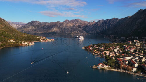 Video – Aerial drone view of small boats leaving trails on calm blue water, moving toward a distant cruise ship and coastal villages - Starpik Stock
