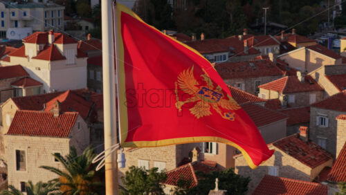 Video – Aerial drone view of the Montenegro flag waving with Budva’s Old Town and the marina in the background - Starpik Stock