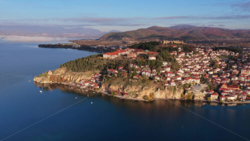 Video – Aerial drone view of the Old Town of Ohrid, North Macedonia peninsula, its red roofed houses, and the modern part of Ohrid stretching along the lakeshore - Starpik Stock