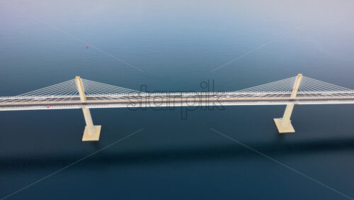 Video – Aerial drone view of the Peljesac Bridge near Komarna, Croatia, partially shrouded in low coastal fog with mountains in the background - Starpik Stock