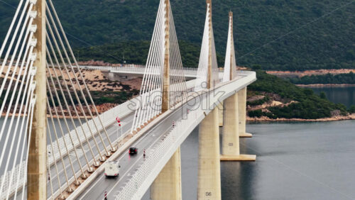 Video – Aerial drone view of the Peljesac Bridge near Komarna, Croatia, partially shrouded in low coastal fog with mountains in the background - Starpik Stock