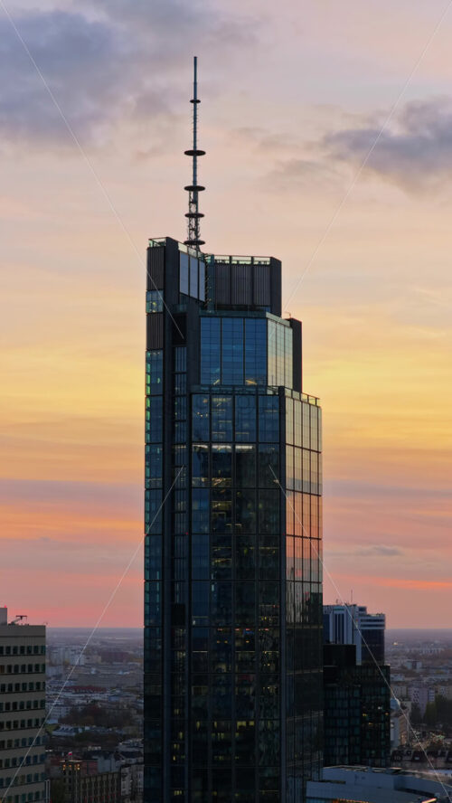 Video – Aerial drone view of the Warsaw Trade Tower featuring its rooftop antenna, set against an overcast evening sky in Warsaw’s Wola district. Vertical - Starpik Stock