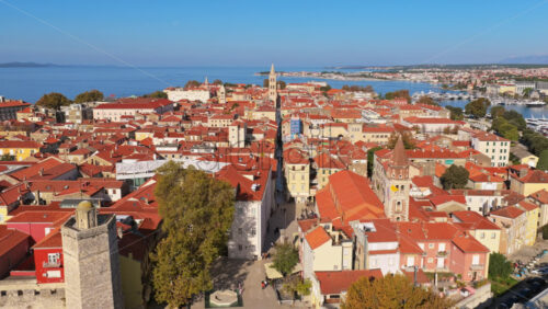 Video – Aerial drone view of the Zadar Old Town with its dense red roofed buildings, medieval towers, narrow stone streets and the Adriatic Sea in the background - Starpik Stock
