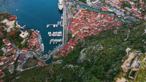 Video – Aerial drone view of the famous zig zag hiking path leading to the fortress, next to the red roofs of Kotor Old Town and the marina - Starpik Stock