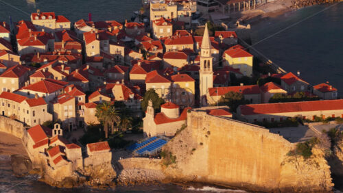 Video – Aerial drone view of the warm toned stone rooftops and narrow streets of Budva’s Old Town. Montenegro - Starpik Stock