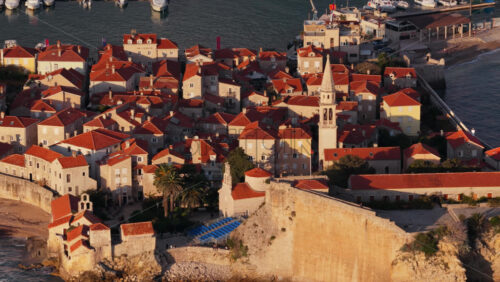 Video – Aerial drone view of the warm toned stone rooftops and narrow streets of Budva’s Old Town. Montenegro - Starpik Stock