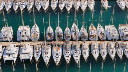 Video – Aerial drone view of tightly packed rows of sailboats lined up in the marina, forming clean geometric patterns over dark blue water. Biograd na Moru, Croatia - Starpik Stock
