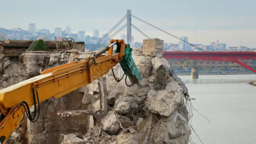 Video - Aerial drone view of heavy demolition machinery crushing concrete on a riverbank construction site in Belgrade, Serbia