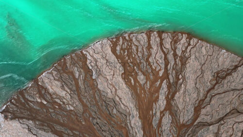 Video - Aerial drone view a mineral lake with bright turquoise water meeting textured white sediment