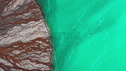 Video - Aerial drone view a mineral lake with bright turquoise water meeting textured white sediment