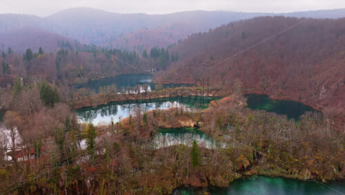 Video - Aerial drone view of fog covered turquoise lakes separated by narrow forested islands at Plitvice Lakes, Croatia