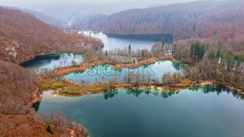 Video - Aerial drone view of fog covered turquoise lakes separated by narrow forested islands at Plitvice Lakes, Croatia