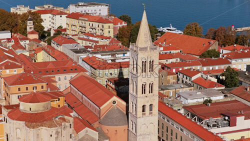 Video - Aerial drone view of the tall bell tower of St. Anastasia Cathedral rising above Zadar's red roofed historic center