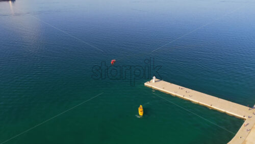 Video - Aerial drone view of Zadar's long waterfront promenade, green urban park, boats, and a white lighthouse at the pier