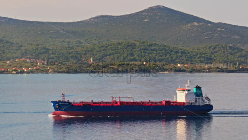 Video - Aerial drone view of an oil tanker traveling across open Adriatic waters with distant mountain ridges and coastal towns visible on the horizon