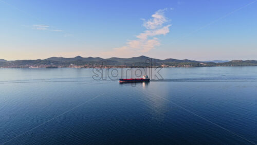 Video - Aerial drone view of an oil tanker traveling across open Adriatic waters with distant mountain ridges and coastal towns visible on the horizon