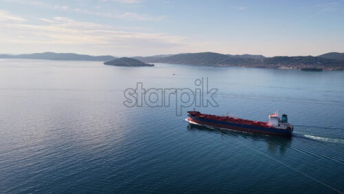 Video - Aerial drone view of an oil tanker traveling across open Adriatic waters with distant mountain ridges and coastal towns visible on the horizon