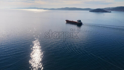 Video - Aerial drone view of an oil tanker traveling across open Adriatic waters with distant mountain ridges and coastal towns visible on the horizon